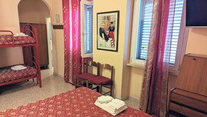 A room with a bunk bed, a single bed, a chair, a desk, a window, and a framed picture on the wall. - Albergo Seggiovia Scanno (Scanno)