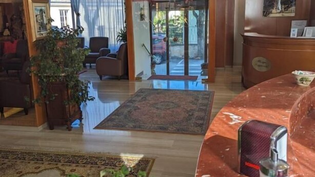 A lobby with a reception desk, seating area, and a large window with curtains. - Albergo Seggiovia Scanno (Scanno)