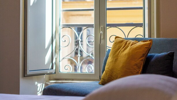 A room with a bed, a window with a view of a balcony, and a door. - Design 18 Charming Rooms (Rome)