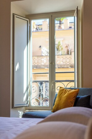 A room with a bed, a window with a view of a balcony, and a door. - Design 18 Charming Rooms (Rome)