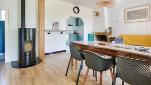 A modern kitchen with a central island, a built-in stove, and a dining area with chairs and a table.