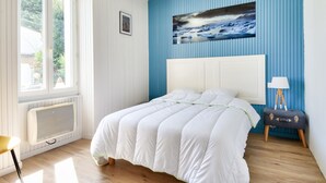 A bedroom with a large bed, a radiator, a window, and a painting on the wall.