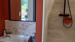 A bathroom with a white sink, a mirror, and a shower with a handheld showerhead. - La Chambrée (Leschelle)