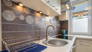 Una cocina moderna con un lavamanos de acero inoxidable, un escurreplatos y un tapete azul en la encimera.