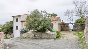 Un edificio de dos pisos con un muro de piedra y un camino de grava.