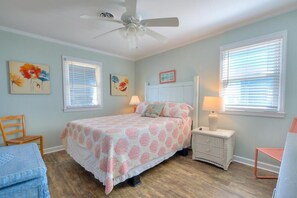 Relax in this serene bedroom with a large bed, ceiling fan, and comfortable seating area.