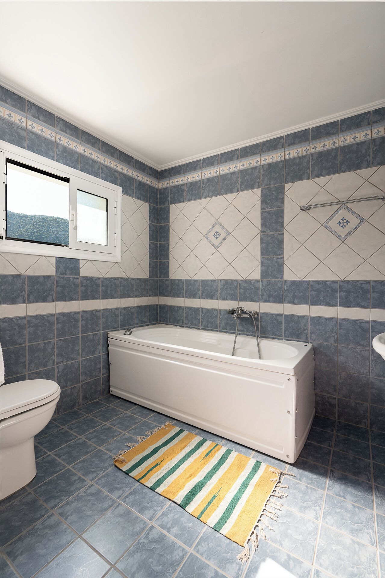 A bathroom with a bathtub, toilet, and window.