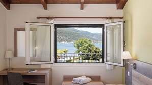 Une chambre à coucher avec un lit, un bureau et une fenêtre donnant sur un lac et des arbres.