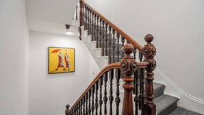 A staircase with wooden balusters and a handrail, carpeted steps, and a painting on the wall. - Cosy Nook | Kitchen w/ Washer & SofaBed | Free Parking (Merseyside)