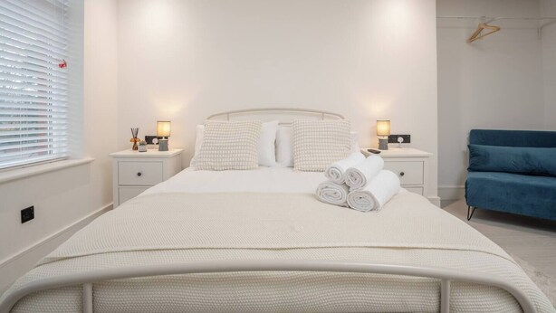 A neatly arranged bedroom with a bed, bedside tables, and a blue chair. - Cosy Nook | Kitchen w/ Washer & SofaBed | Free Parking (Merseyside)