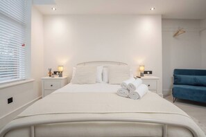 A neatly arranged bedroom with a bed, bedside tables, and a blue chair. - Cosy Nook | Kitchen w/ Washer & SofaBed | Free Parking (Merseyside)