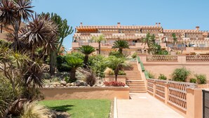 A multi-story hotel with a terraced garden and palm trees.