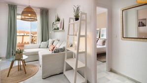 A modern living room with a sofa, a glass coffee table, a ladder shelf, and a large mirror.