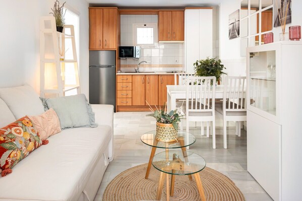 A modern kitchen with wooden cabinets, a stainless steel refrigerator, and a white dining area with a glass table.