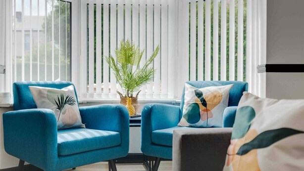 A modern living room with two blue armchairs, a small table, and a potted plant. - 10Min Walk to Stadium | SofaBed | W/M & Dishwasher (Anfield)