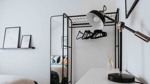 A modern room with a bed, a desk, a lamp, a mirror, and a clothing rack. - 10Min Walk to Stadium | SofaBed | W/M & Dishwasher (Anfield)