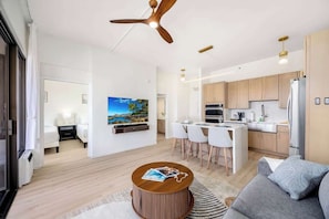 Una sala de estar moderna con un sofá, una mesa de centro, un televisor y una zona de cocina con un comedor.