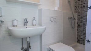 A modern bathroom with a white sink, toilet, and shower.