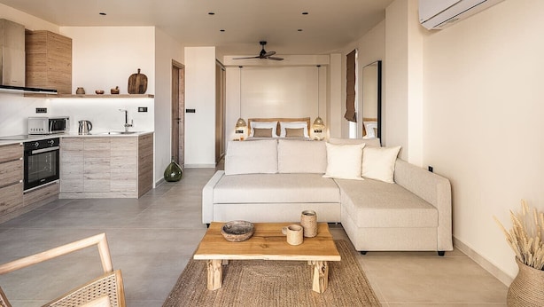A modern living room with a sofa, coffee table, and kitchen area. - Nomada 1 | Chania City Center (Chania)