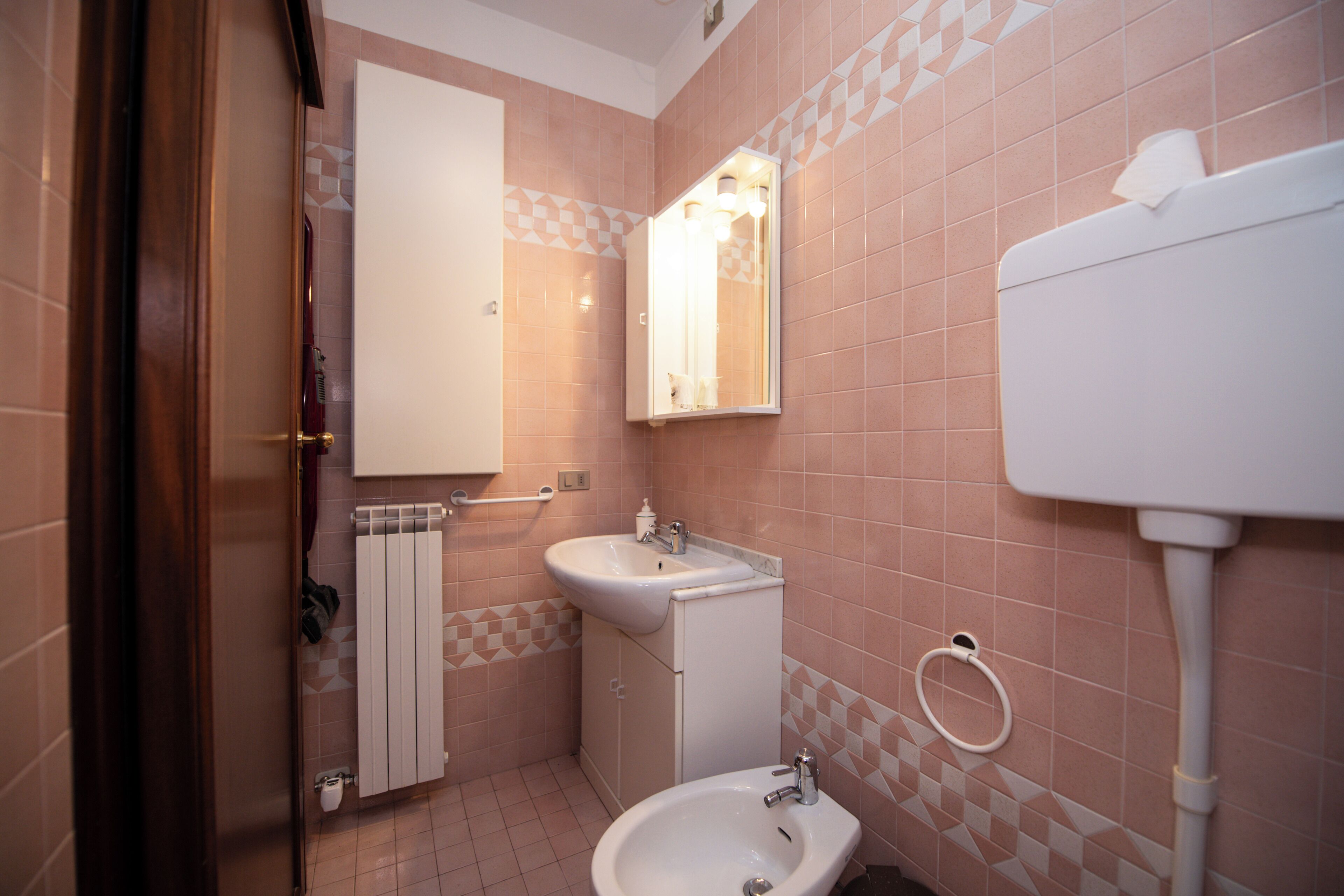 Ein Badezimmer mit Waschbecken, Spiegel, Toilette und Handtuchwärmer.