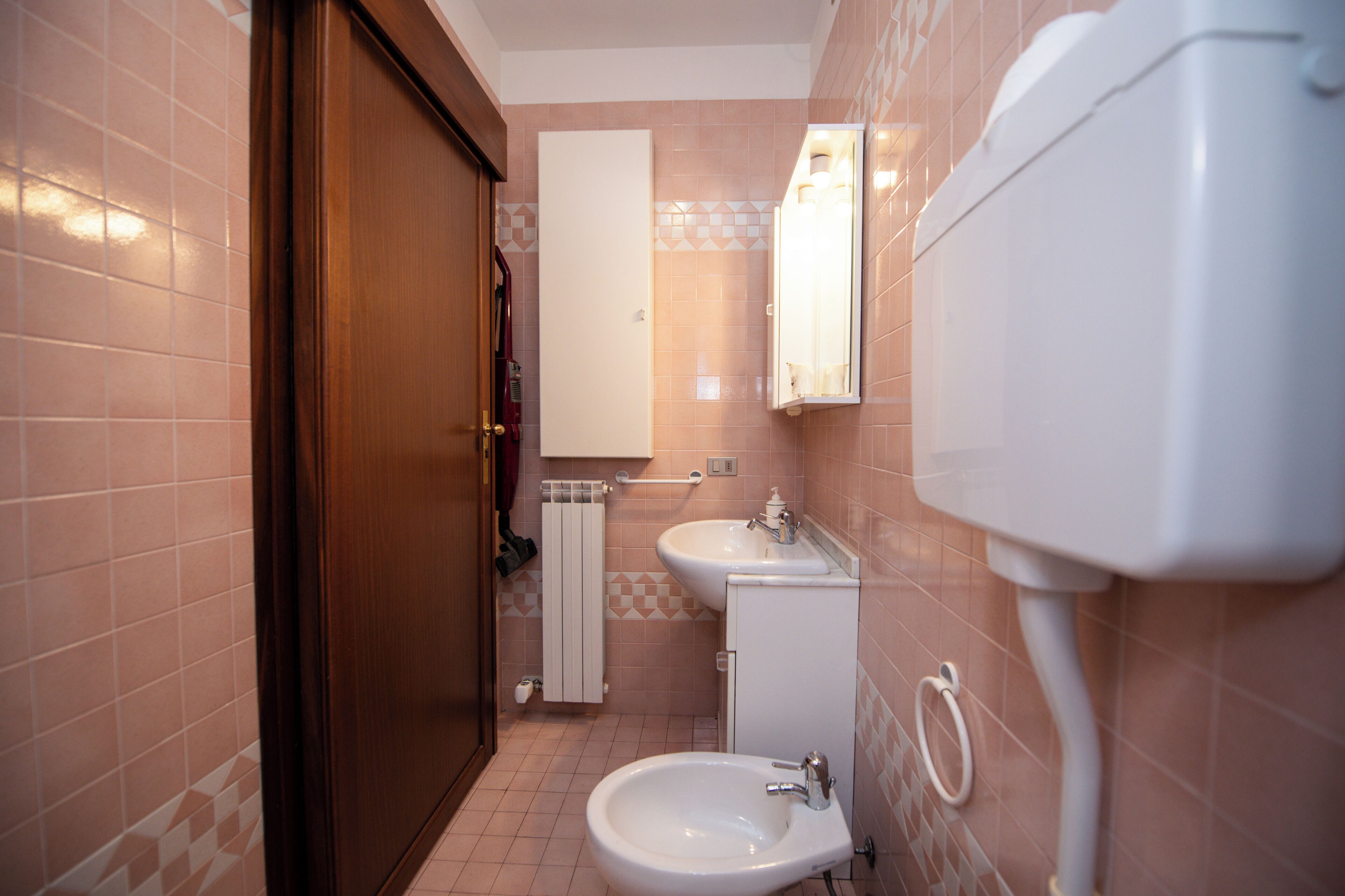 A bathroom with a sink, toilet, and mirror.