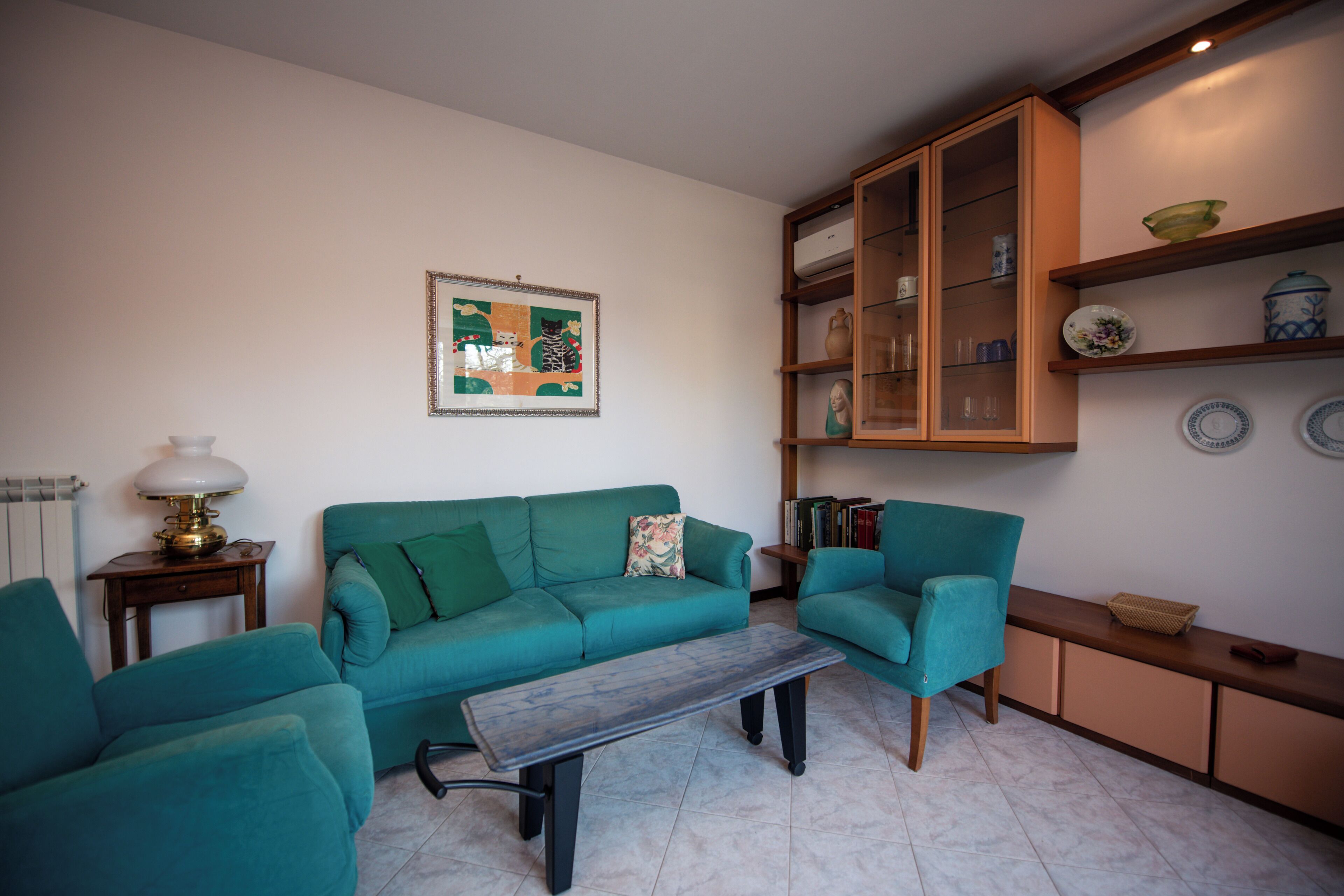 A living room with teal sofas, a coffee table, and a cabinet with decorative items.