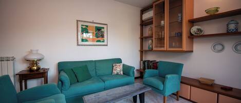 A living room with teal sofas, a coffee table, and a cabinet with decorative items.