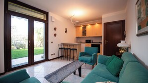 A living room with a sofa, a coffee table, and a kitchen area with a dining set.