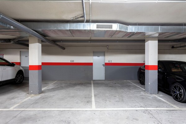 Un parking avec des piliers en béton, des places de stationnement numérotées et une voiture blanche garée dans la place numéro 60.