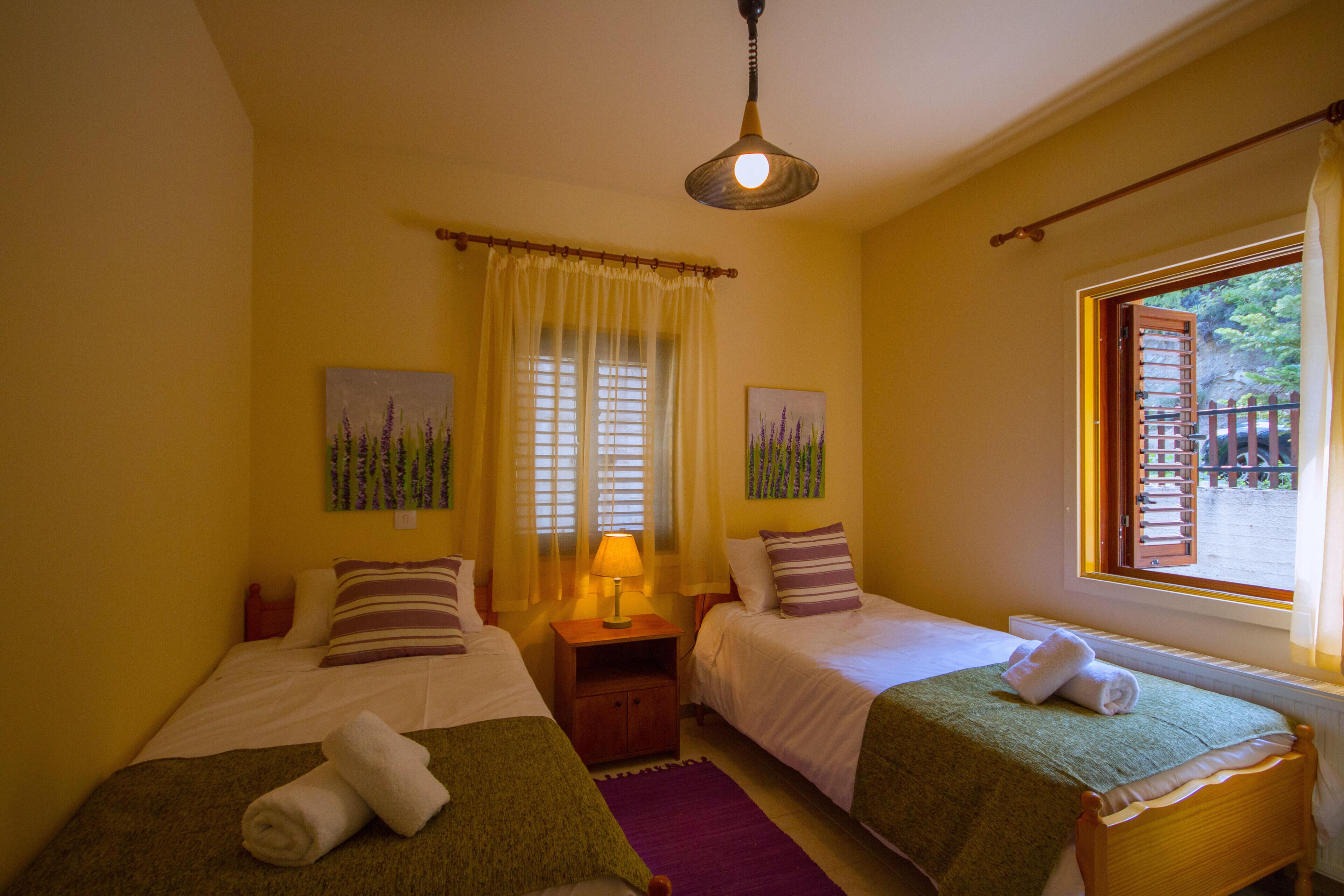 Habitación con dos camas, una mesita de noche, ventanal con vistas y una lámpara en el techo.