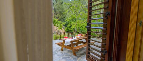 A wooden door with a view of a stone patio with a picnic table and a watermelon.