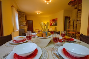 Une table à manger dressée avec des assiettes, des bols, des verres et un centre de table composé de pain et d’un pot.