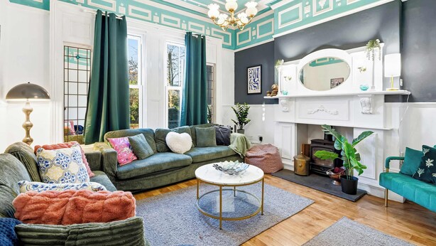 Un salon avec un canapé vert, une table basse ronde et une cheminée.