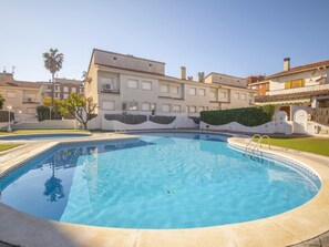Una piscina rodeada de edificios con balcones y un cielo despejado.