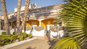 Un bâtiment à la façade jaune, doté de balcons blancs et bordé de palmiers.