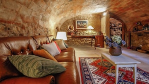 A cozy living room with a leather sofa, a patterned rug, and a rustic brick wall. - Francigena Pergola Apartment Shared Pool (Gambassi Terme)