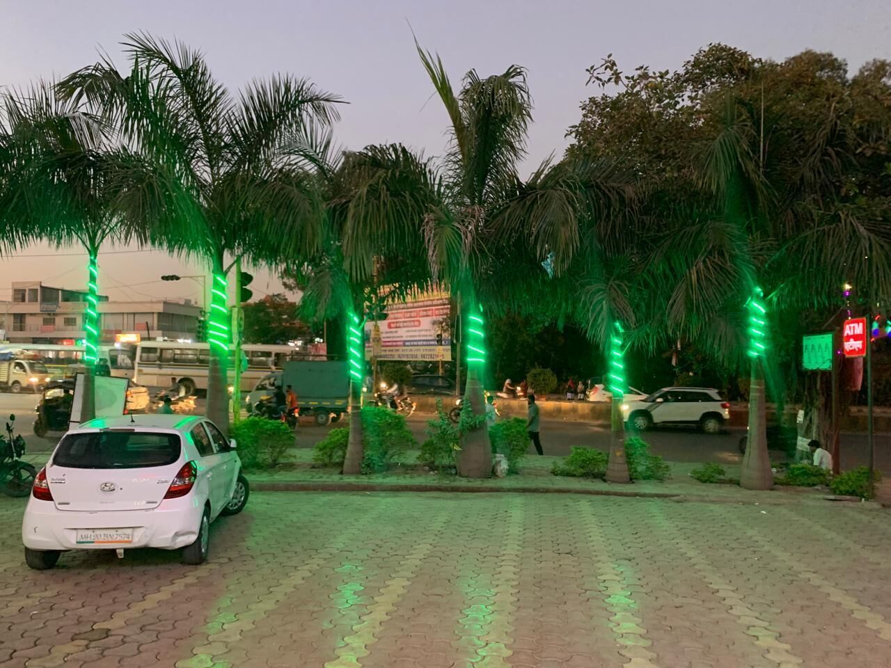 A paved area with palm trees and a white car parked on the side.