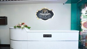En receptionsdisk med en skylt som visar texten ”OPAL PLAZA HOTEL” och en blomsterdekoration ovanpå.