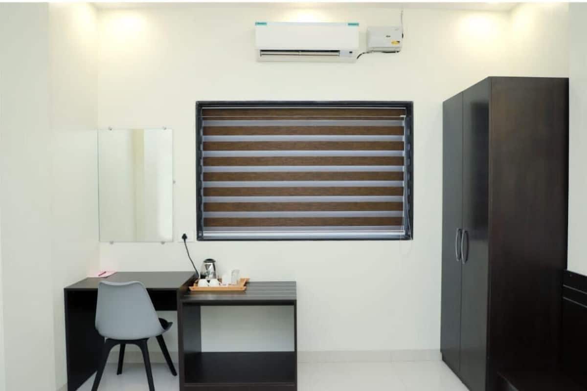 A compact room with a desk, chair, and wardrobe.