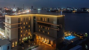 A modern hotel with a rooftop pool, a waterfront view, and a well-lit entrance. - Bickley Park Hotel (Lekki)