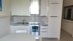 A modern kitchen with white cabinets, stainless steel appliances, and a tiled backsplash. - Charming 1-bedroom apartment in Lerici with WiFi, AC (Lerici)