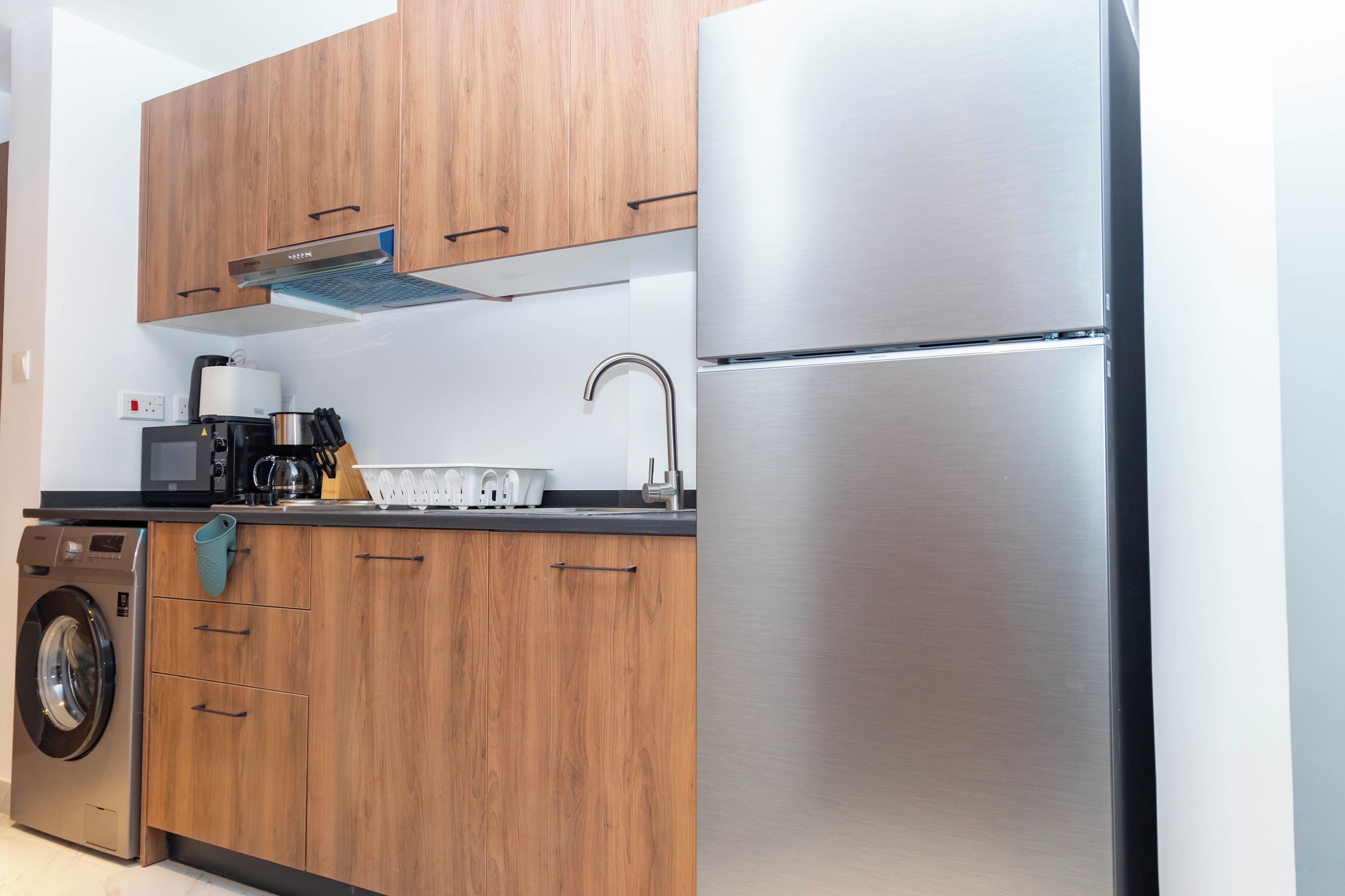 A modern kitchen with wooden cabinets, stainless steel appliances, and a built-in washing machine.