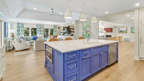 A modern kitchen with blue cabinets, a large island, pendant lights, and a view to the dining area. - FULLY RENOVATED, Gorgeous 3 Bedroom Sea Pines Home - Private Pool - Golf View (Hilton Head Island)