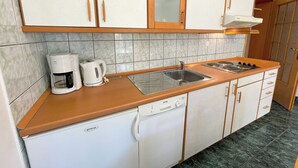 A kitchen with white cabinets, a stainless steel sink, a coffee maker, and a dishwasher. - Apartman Villa Ljiljana 6 (Jadranovo)