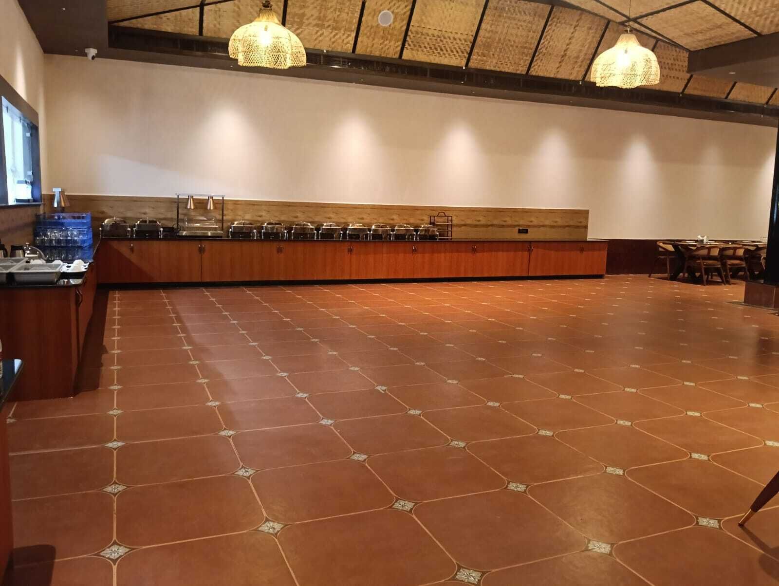 A spacious room with a long counter, tiled floor, and hanging pendant lights.