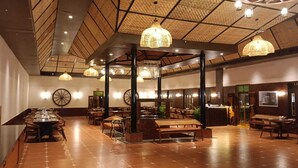 Eine geräumige Lobby mit hohen Decken, großen Fenstern und einer zentralen Sitzgruppe mit Tischen und Stühlen.