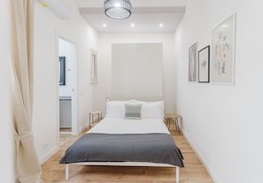 A bedroom with a bed, bedside tables, a hanging light fixture, and framed artwork on the wall. - Acquamarina Apartment  (Trapani)