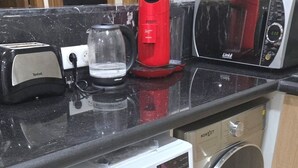 A compact kitchen with a washing machine, a toaster, and a red appliance on the countertop. - Apartment downtown Marrakech Guéliz (MARRAKECH)