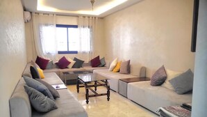 A modern living room with two sofas, a coffee table, and a small trash bin. - Apartment downtown Marrakech Guéliz (MARRAKECH)