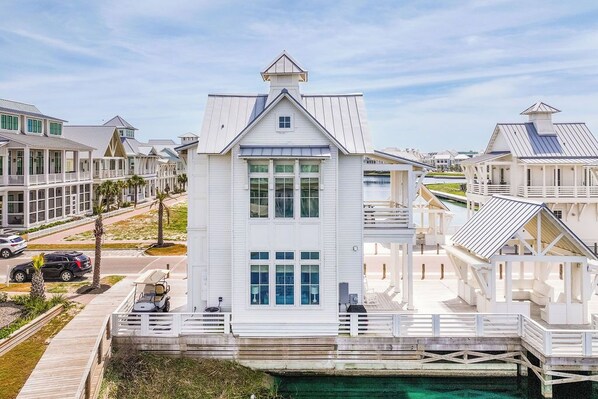 A coastal house with a dock, multiple decks, and a clear view of the water.